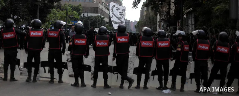 Egyptian riot police stand guard outside the Shura Council, the upper house of parliament where the Constituent Assembly drafted the country's new constitution, as protesters against Egypt's President Mohamed Morsi chant...