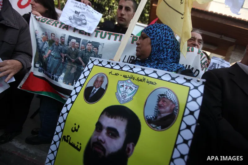 Palestinians hold pictures of prisoners held in the Israeli jails during a rally in Gaza city on December 31, 2012. in solidarity with hunger-striking detainees held by Israel to demand their release from detention witho...