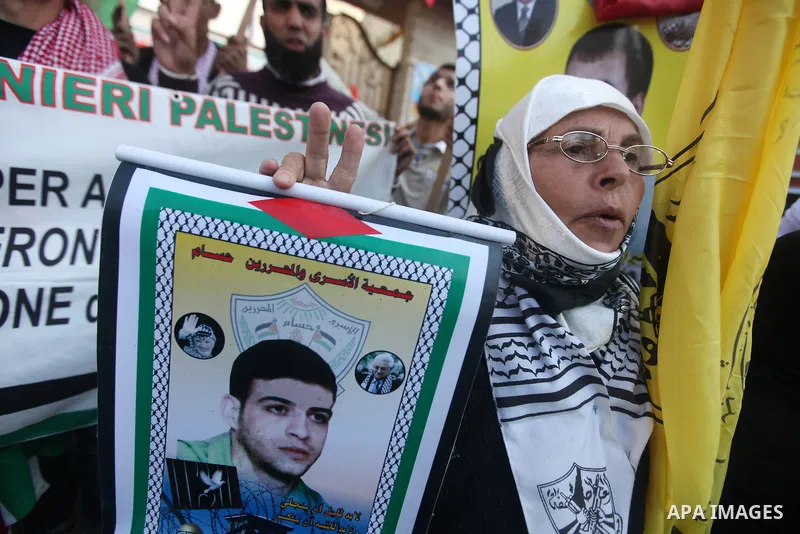 Palestinians hold pictures of prisoners held in the Israeli jails during a rally in Gaza city on December 31, 2012. in solidarity with hunger-striking detainees held by Israel to demand their release from detention witho...