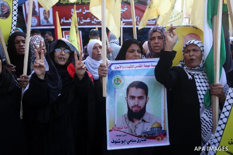 Palestinians hold pictures of prisoners held in the Israeli jails during a rally in Gaza city on December 31, 2012. in solidarity with hunger-striking detainees held by Israel to demand their release from detention witho...