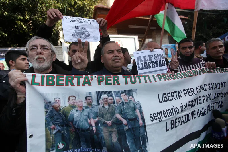 Palestinians and foreign protesters hold pictures of prisoners held in the Israeli jails during a rally in Gaza city on December 31, 2012. in solidarity with hunger-striking detainees held by Israel to demand their relea...