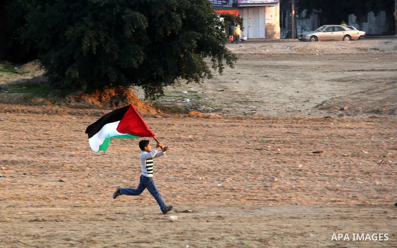 A Palestinian child holds his national flag as he runs during a rally in Gaza city on December 31, 2012. The Gaza branch of Palestinian president Mahmud Abbas's Fatah party said on Friday it will mark its anniversary in...