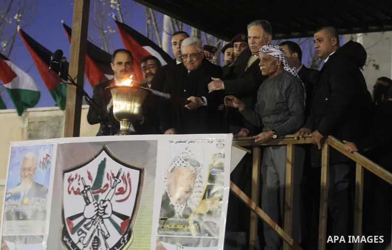 Palestinian President Mahmud Abbas lights a flame as thousands of Palestinians look on, on the eve of the 48th anniversary of the formation on the Fatah movement, on December 31, 2012, in the West Bank city of Ramallah....