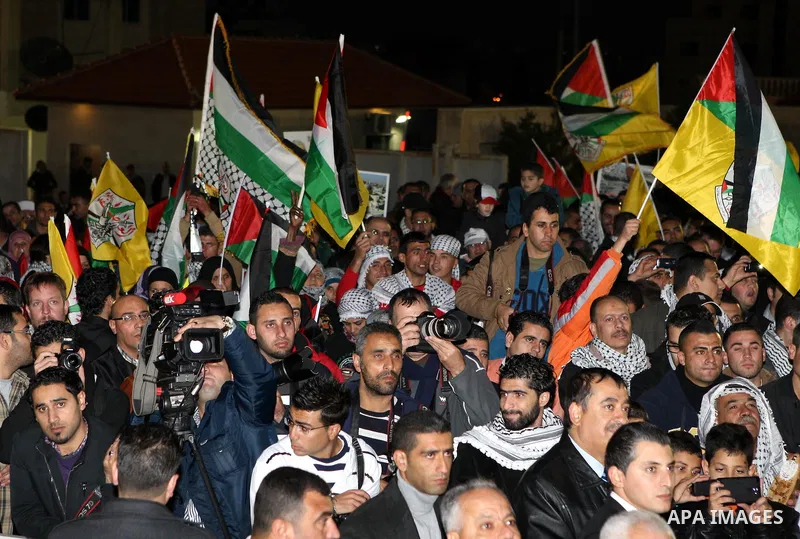 Palestinians wave their national flag during a rally on the eve of the 48th anniversary of the formation on the Fatah movement, on December 31, 2012, in the West Bank city of Ramallah. The Fatah anniversary commemorates...