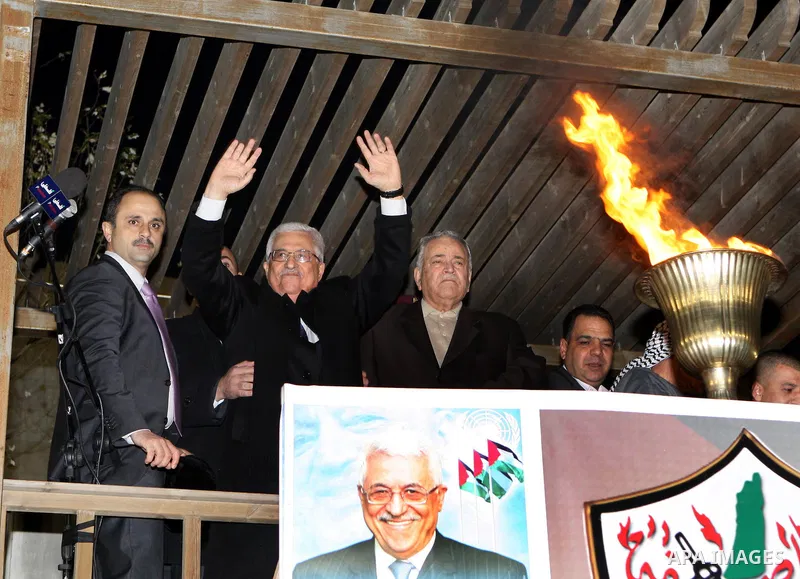 Palestinian President Mahmud Abbas lights a flame as thousands of Palestinians look on, on the eve of the 48th anniversary of the formation on the Fatah movement, on December 31, 2012, in the West Bank city of Ramallah....