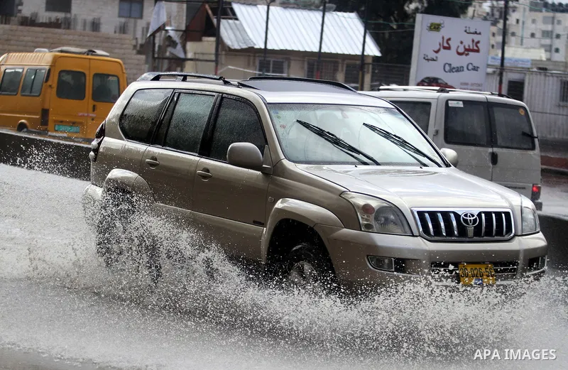 A car drives on a flooded street in the West Bank city of Ramallah during a windy winter day on January 7, 2013. Photo by Issam Rimawi