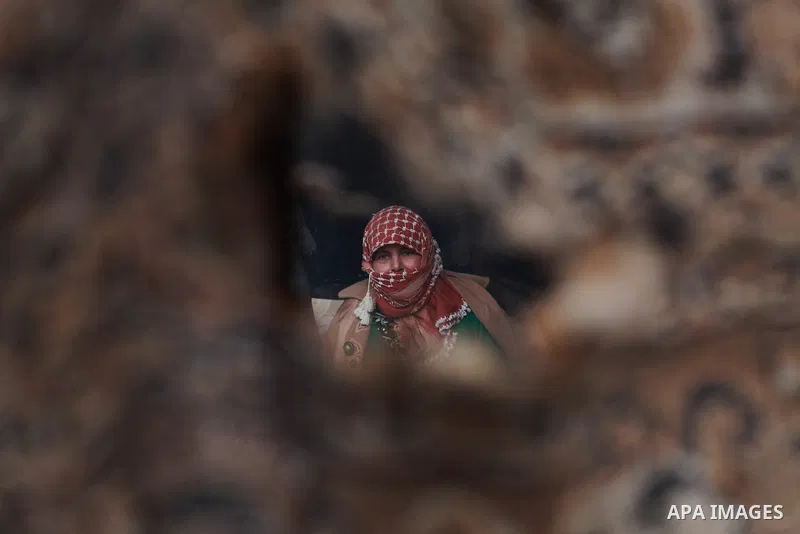 A Palestinian bedouin woman warm herself by a fire inside her shack on a windy winter day in the central Gaza Strip January 10, 2013. A storm has hit the eastern Mediterranean coast and heavy rains with flooding are fore...