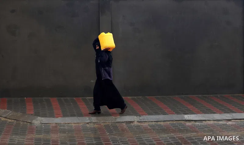 A Palestinian bedouin woman fill bottles with water in the central Gaza Strip January 10, 2013. A storm has hit the eastern Mediterranean coast and heavy rains with flooding are forecast in Israel and the Palestinian ter...