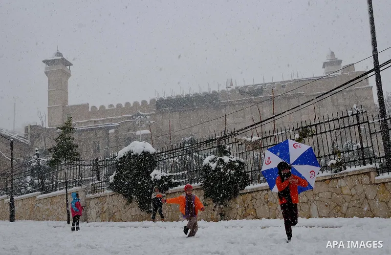 Palestinian kids play with the snow in front of the Ibrahimi Mosque or the Tomb of the Patriarchs on January 10, 2013 in the West Bank city of Hebron. As temperatures plummeted, the bitter winds and rain that have batter...