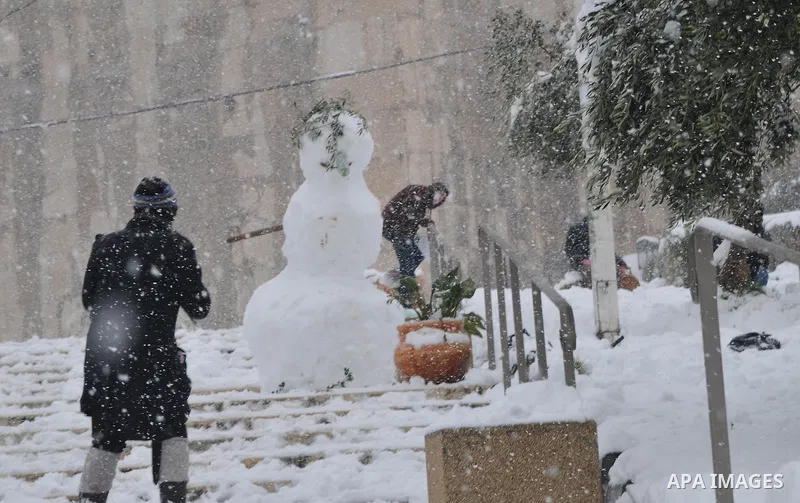 Palestinians play with snow balls after heavy snow falls in the West Bank City of Hebron as wintry weather swept through the region 10 January 2013. Photo by Mamoun Wazwaz