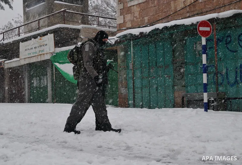 A Jewish settler walks on the snow in front of the Ibrahimi Mosque or the Tomb of the Patriarchs on January 10, 2013 in the West Bank city of Hebron. As temperatures plummeted, the bitter winds and rain that have battere...