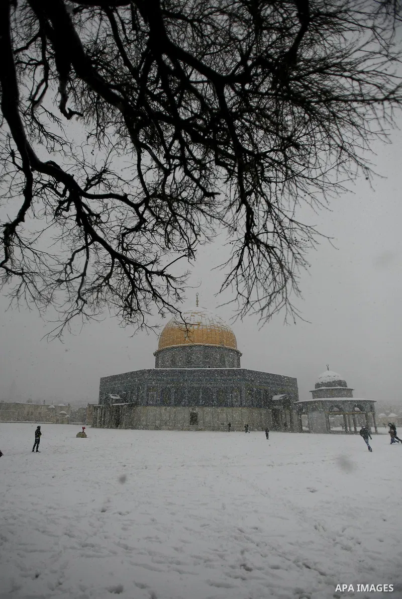 Palestinians walk in front of the Dome of the Rock mosue as snow falls at the Al-Aqsa mosque compound in the old city of Jerusalem on January 10, 2013. Jerusalem was transformed into a winter wonderland after heavy overn...