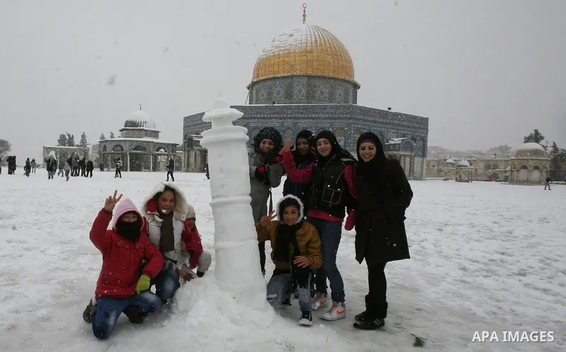 Palestinian children play with snow at the Al-Aqsa mosque compound in the old city of Jerusalem on January 10, 2013. Jerusalem was transformed into a winter wonderland after heavy overnight snowfall turned the Holy City...
