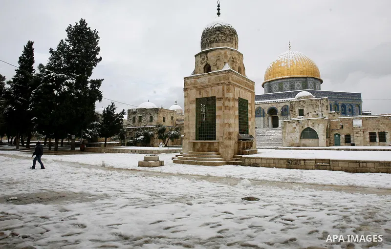 A Palestinian man walks in front of the Dome of the Rock mosue as snow falls at the Al-Aqsa mosque compound in the old city of Jerusalem on January 10, 2013. Jerusalem was transformed into a winter wonderland after heavy...