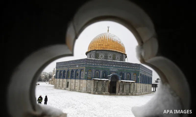 Palestinians walk in front of the Dome of the Rock mosue as snow falls at the Al-Aqsa mosque compound in the old city of Jerusalem on January 10, 2013. Jerusalem was transformed into a winter wonderland after heavy overn...