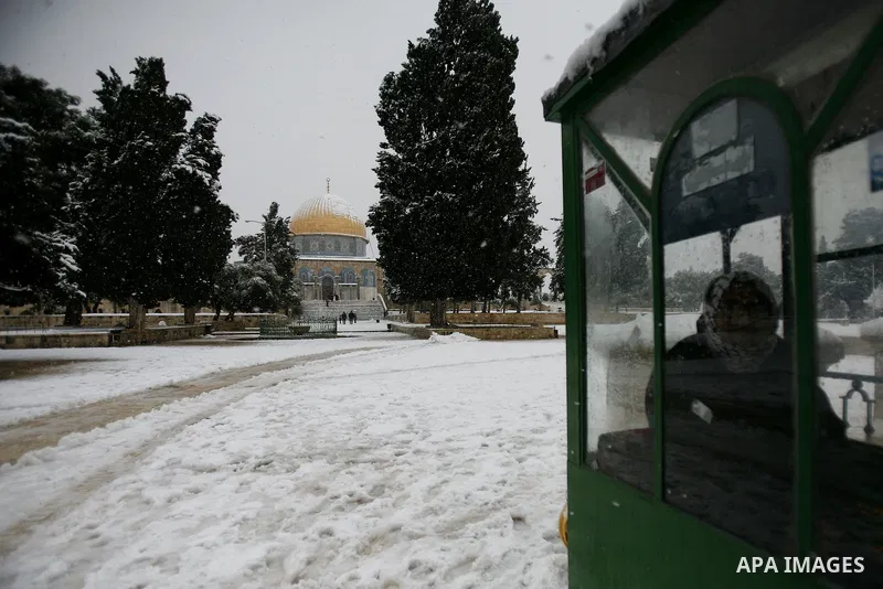 Palestinians walk in front of the Dome of the Rock mosue as snow falls at the Al-Aqsa mosque compound in the old city of Jerusalem on January 10, 2013. Jerusalem was transformed into a winter wonderland after heavy overn...