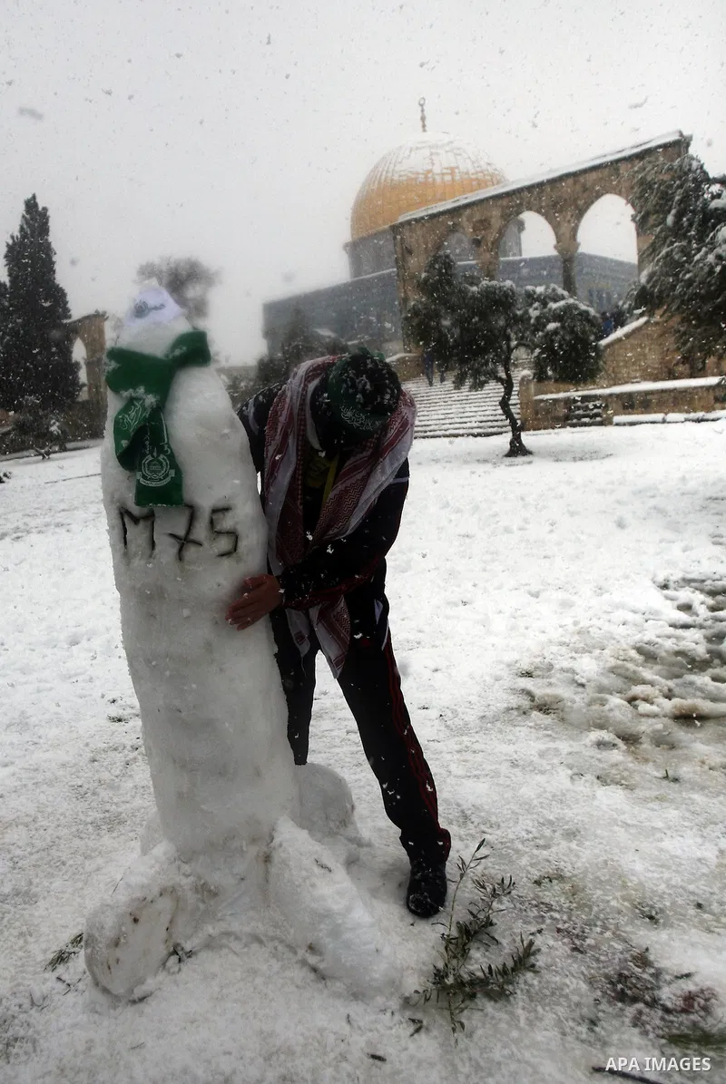 A Palestinian man builds a Hamas handmade M75 rocket by snow at the Al-Aqsa mosque compound in the old city of Jerusalem on January 10, 2013. Jerusalem was transformed into a winter wonderland after heavy overnight snowf...