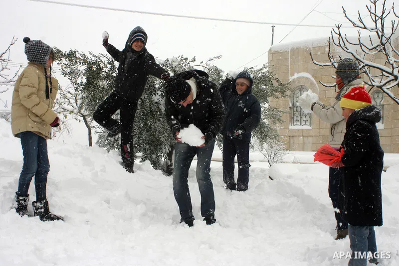 Palestinian children play with snow balls in the West Bank city of Hebron on January 10, 2013. Abnormal storms, which for four days have blasted the Middle East with rain, snow and hail, leave swathes of Israel and Jorda...