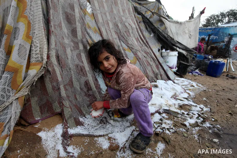 A Palestinian Beduin girl play in snow next to her tent as wintry weather swept through the region, in Gaza city on 10 January 2013. Abnormal storms, which for four days have blasted the Middle East with rain, snow and h...