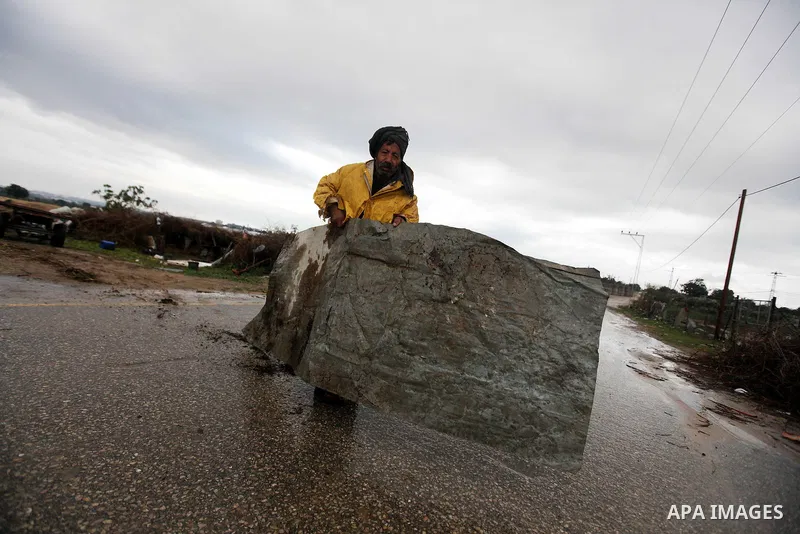 A Palestinian farmer carries a tinplate board as wintry weather swept through the region, in Gaza city on 10 January 2013. Abnormal storms, which for four days have blasted the Middle East with rain, snow and hail, leave...