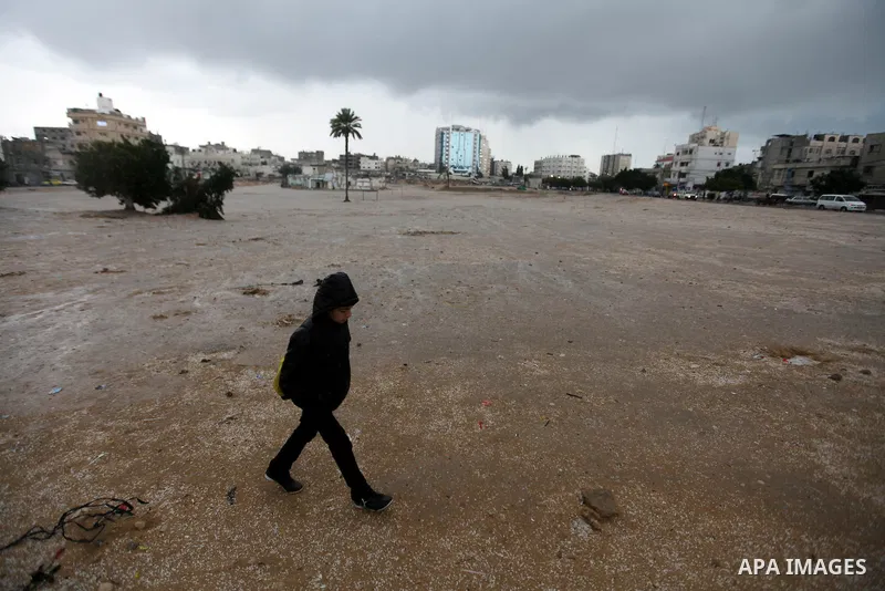 A Palestinian man walks at a street as wintry weather swept through the region, in Gaza city on 10 January 2013. Abnormal storms, which for four days have blasted the Middle East with rain, snow and hail, leave swathes o...