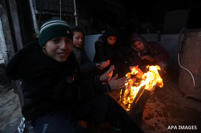 Palestinians warm themselves as wintry weather swept through the region, in Gaza city on 10 January 2013. Abnormal storms, which for four days have blasted the Middle East with rain, snow and hail, leave swathes of Israe...