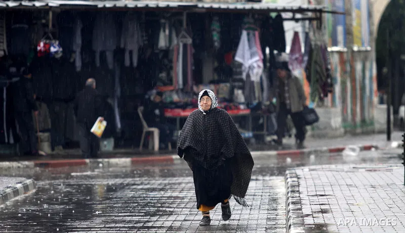 A Palestinian old woman walks at a street as wintry weather swept through the region, in Gaza city on 10 January 2013. Abnormal storms, which for four days have blasted the Middle East with rain, snow and hail, leave swa...