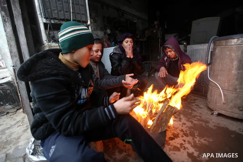 Palestinians warm themselves as wintry weather swept through the region, in Gaza city on 10 January 2013. Abnormal storms, which for four days have blasted the Middle East with rain, snow and hail, leave swathes of Israe...