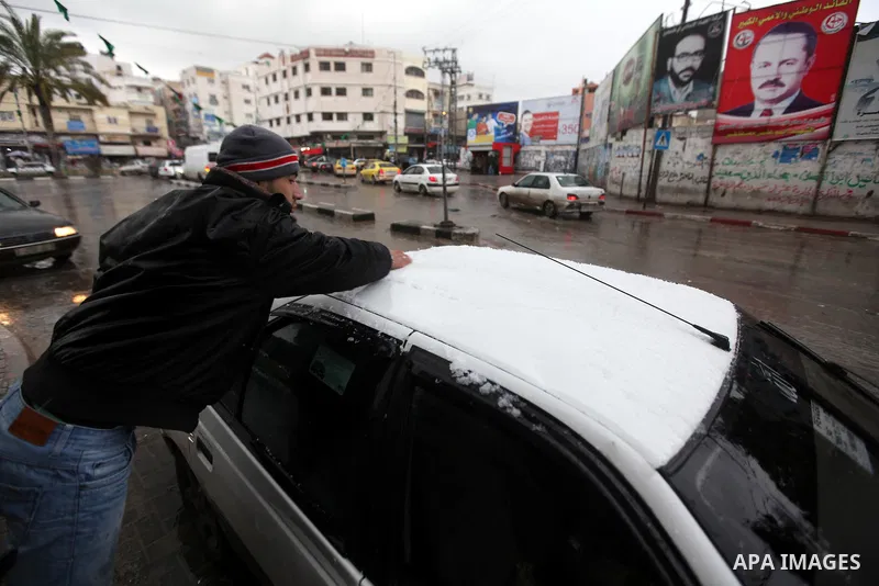 A Palestinian man remove the snow on his car as wintry weather swept through the region, in Gaza city on 10 January 2013. Abnormal storms, which for four days have blasted the Middle East with rain, snow and hail, leave...