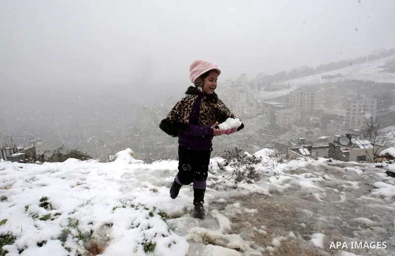 A Palestinian child play with snow balls in the West Bank city of Nablus on January 10, 2013. Abnormal storms, which for four days have blasted the Middle East with rain, snow and hail, leave swathes of Israel and Jordan...