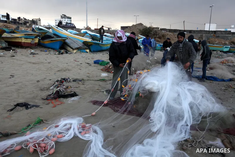 Palestinian fishermen combine their nets during a storm on January 10, 2013 in Gaza City. In Gaza, cold weather and heavy rain flooded several of the tunnels running between the territory and Egypt as in the West Bank ci...