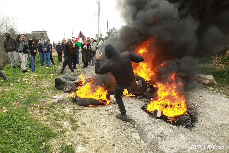 A Palestinian protester burns a tire during clashes with Israeli soldiers following a demonstration against the expropriation of Palestinian land by Israel in the village of Kfar Qaddum, near the occupied West Bank city...