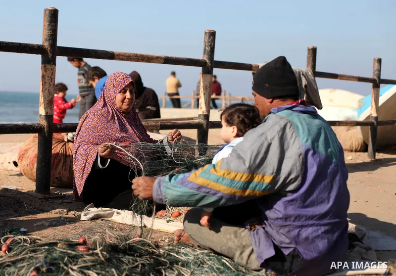 A Palestinian fisherman with his wife fix a fishing nets at the beach, in al-Shati refugee camp in Gaza city on January 20, 2013. Photo by Majdi Fathi