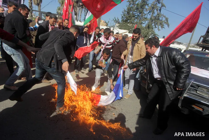 Palestinian protesters burn French flag, during a protest outside the French Cultural Center calling for the release of Lebanese militant Georges Ibrahim Abdallah (portrait L) and Ahmed Saadat, leader PFLP (portrait R),...