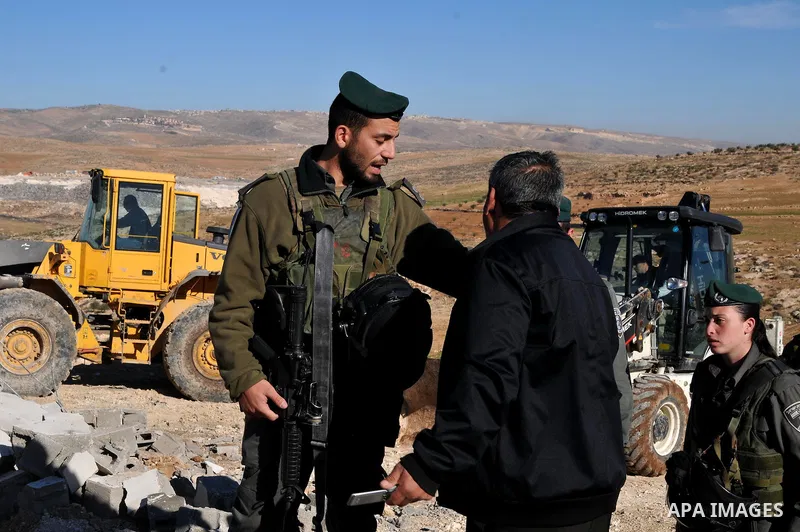 A Palestinian man is restrained by Israeli soldiers as Israeli bulldozers demolish man-made reservoir near the village of Yatta, near the West Bank city of Hebron, 21 January 2013. The reservoir was reportedly located in...