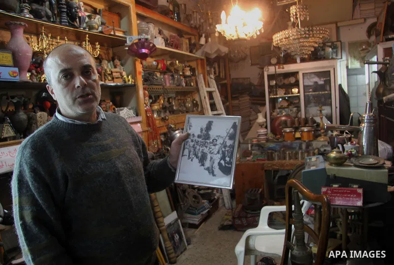 A Palestinian vendor displays an old photo shows Palestinian children during military exercises, in his antiques store in Gaza city on January 20, 2013. Photo by Ezz al-Zanoon