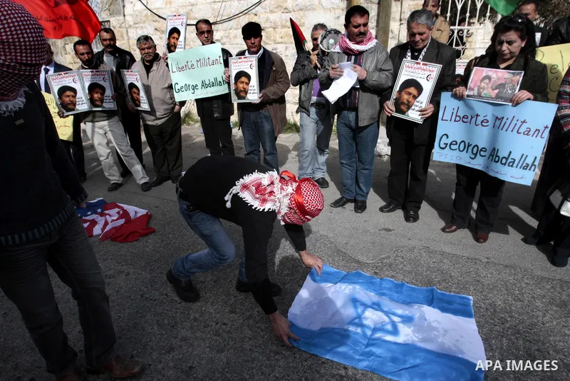 Palestinian protesters burn French flag and israeli, during a protest outside the French Cultural Center calling for the release of Lebanese militant Georges Ibrahim Abdallah and Ahmed Saadat, leader PFLP, in the West Ba...