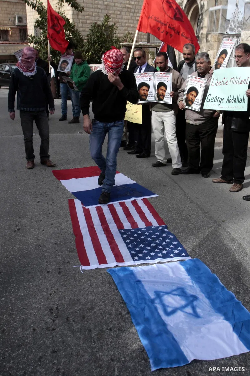 Palestinian protesters burn French flag and israeli, during a protest outside the French Cultural Center calling for the release of Lebanese militant Georges Ibrahim Abdallah and Ahmed Saadat, leader PFLP, in the West Ba...