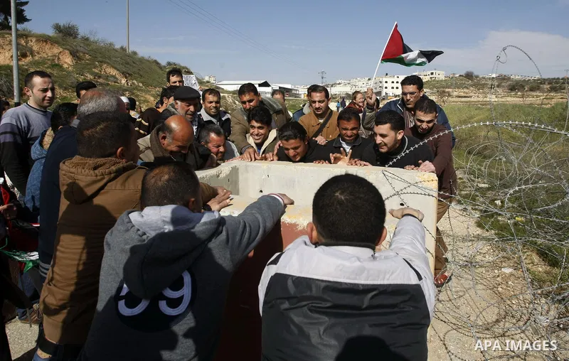 Palestinian protesters try to remove cement barriers which placed by Israeli soldiers, and blocked an entrance for Hebron, near the Beit Hajai settlement, southern the West Bank city of Hebron on January 25, 2013. Photo...
