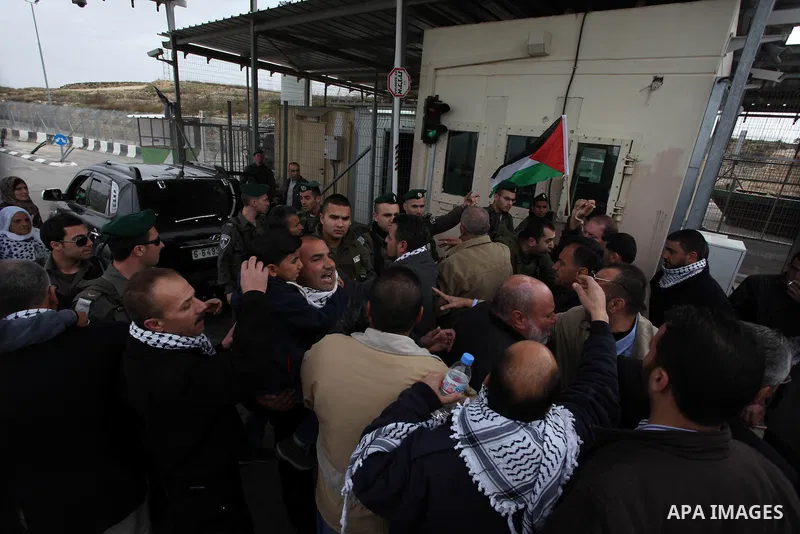 Palestinian protesters argue with Israeli soldiers as they try to cross an Israeli checkpoint to join Friday prayers in confiscated lands by Israeli army on January 25, 2013 in the West Bank village of Beit Iksa. Activis...