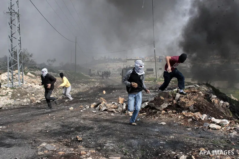 Palestinian protesters throw stones towards Israeli soldiers during a protest against the expropriation of Palestinian land by Israel on January 25, 2013 in the village of Kafr Qadum, near Nablus, in the occupied West Ba...