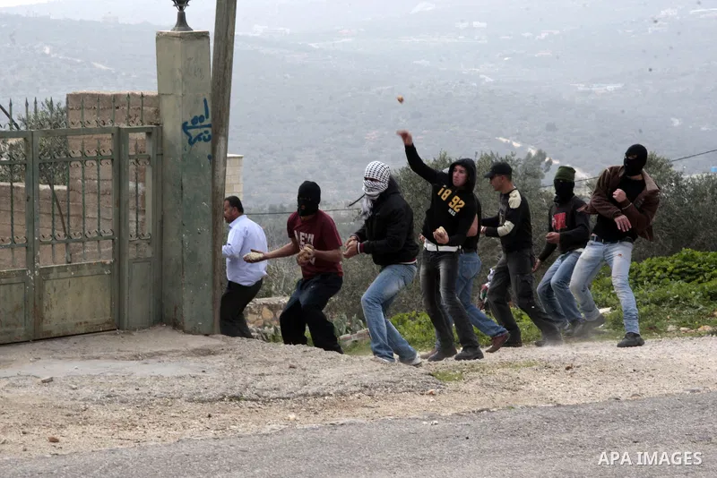 Palestinian protesters throw stones towards Israeli soldiers during a protest against the expropriation of Palestinian land by Israel on January 25, 2013 in the village of Kafr Qadum, near Nablus, in the occupied West Ba...