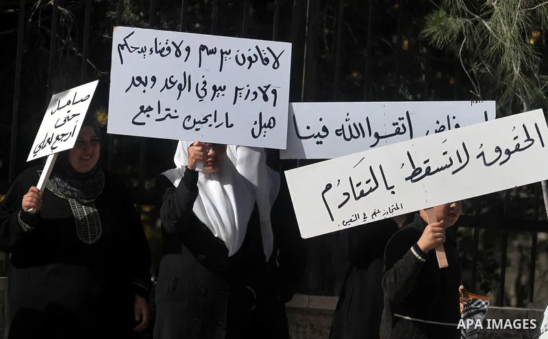 Palestinian teachers and graduates who were barred from employment by Ministry of Education, hold placards during a protest in front of Council of Ministers, demanding the government back them to their works in the West...