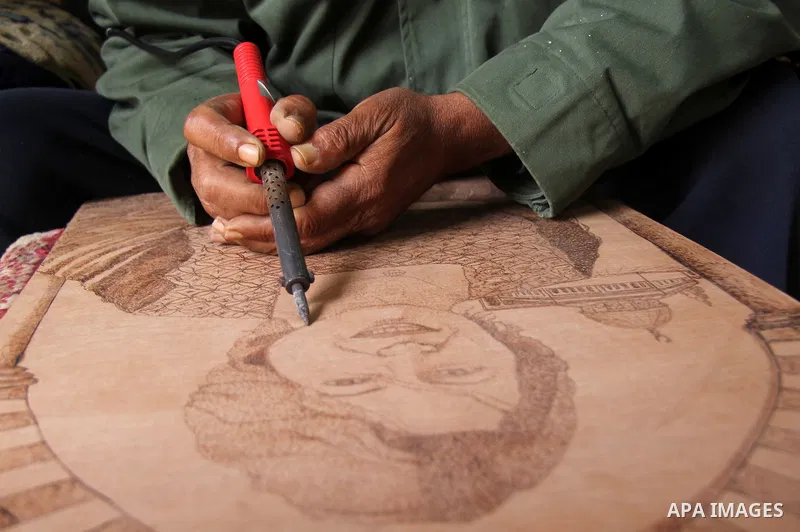 Palestinian artist Abdul Latif abu Karsh, 63 years, draws by burning wood in his house at al-Shati refugee camp in Gaza city on January 30, 2013. Abu Karsh stints several arts like rock sculpture, wood burning art, coppe...