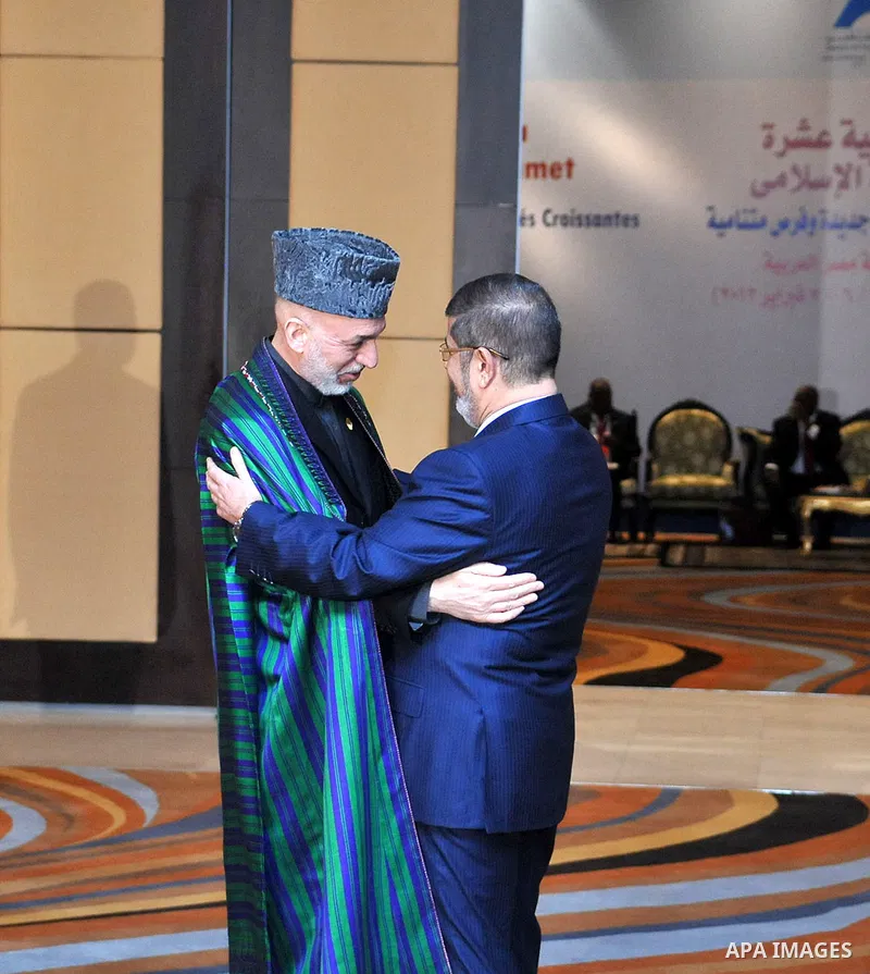 A handout picture released by the Egyptian presidency shows Egyptian President Mohamed Morsi (R) greeting his Afghan counterpart Hamid Karzai during the 12th summit of the Organisation of Islamic Cooperation (OIC) in Cai...