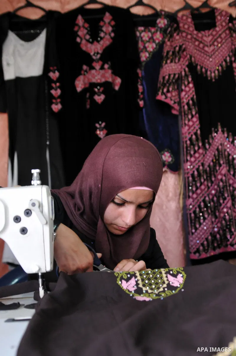 Ayat al-Mahareeq, 22 years old, A Palestinian tailor works at her workshop in the West Bank city of Hebron, on Feb. 16, 2013. al-Mahareeq succeeded in merging the touches of Palestinian traditional embroidery with modern...