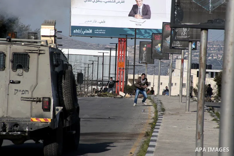 A Palestinian demonstrator throws stones at Israeli border police during clashes at Huwwara checkpoint near Nablus, the West Bank, 21 February 2013. According to Palestinian sources, 12 Palestinians were injured during t...
