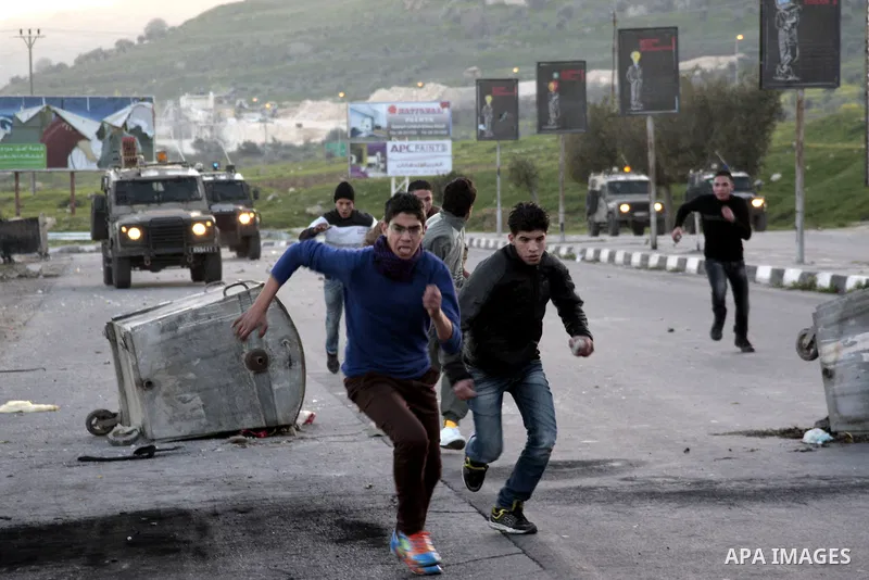 Palestinian demonstrators run to seek cover during clashes at Huwwara checkpoint near Nablus, the West Bank, 21 February 2013. According to Palestinian sources, 12 Palestinians were injured during the clashes,and five ar...