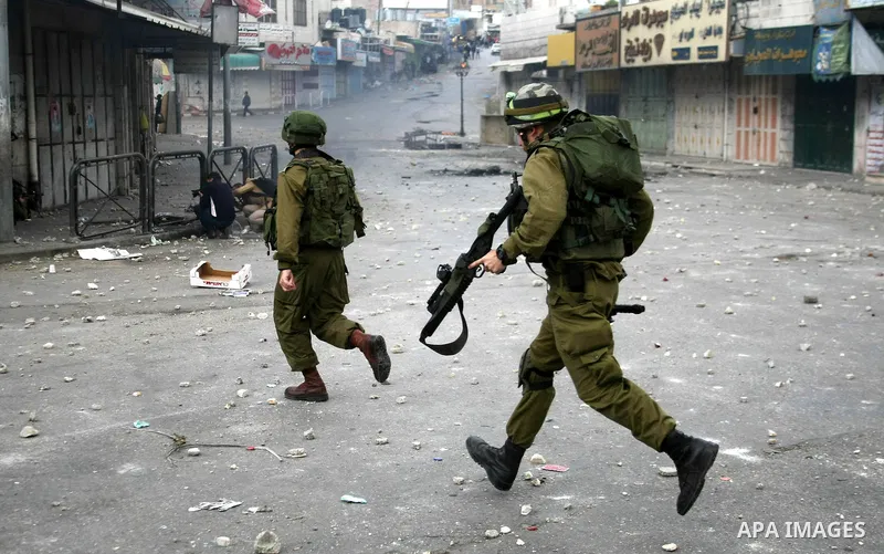 Israeli security forces stand opposite Palestinian protesters during clashes in the West Bank city of Hebron, on February 24, 2013 following the death of a Palestinian prisoner held in Israel. Some 3,000 Palestinians hel...