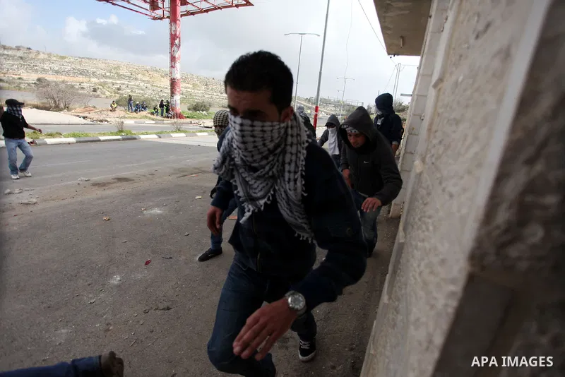 Palestinian protesters take cover during clashes next to the Israeli military prison 'Ofer' in Beitunya, south of the West Bank city of Ramallah, on February 24, 2013 following the death of a Palestinian prisoner held in...